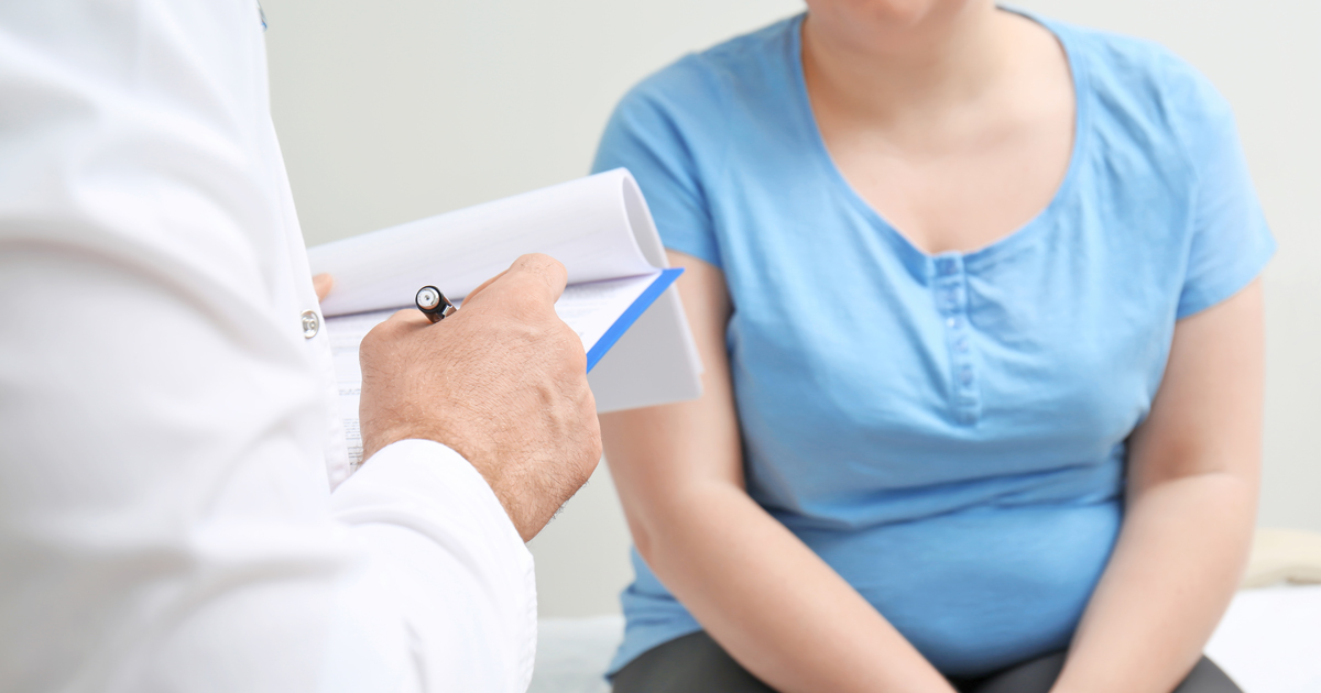 A physician taking notes while speaking with a female patient
