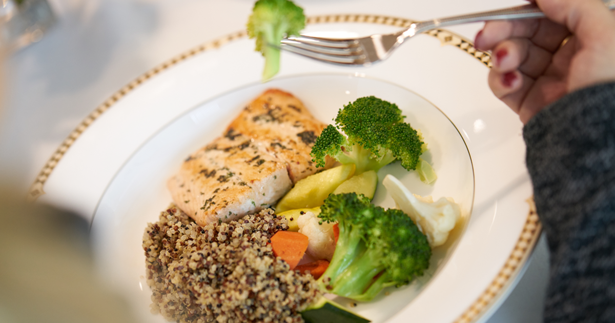 A plate of healthy food including salmon, broccoli, and wild rice
