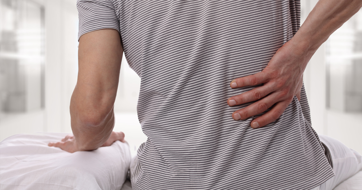 a male patient experiencing back pain with his hand on his back