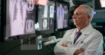 doctor crosses his arms while looking at lung x ray diagrams