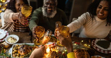 A smiling family raising their glasses to cheers over a holiday meal