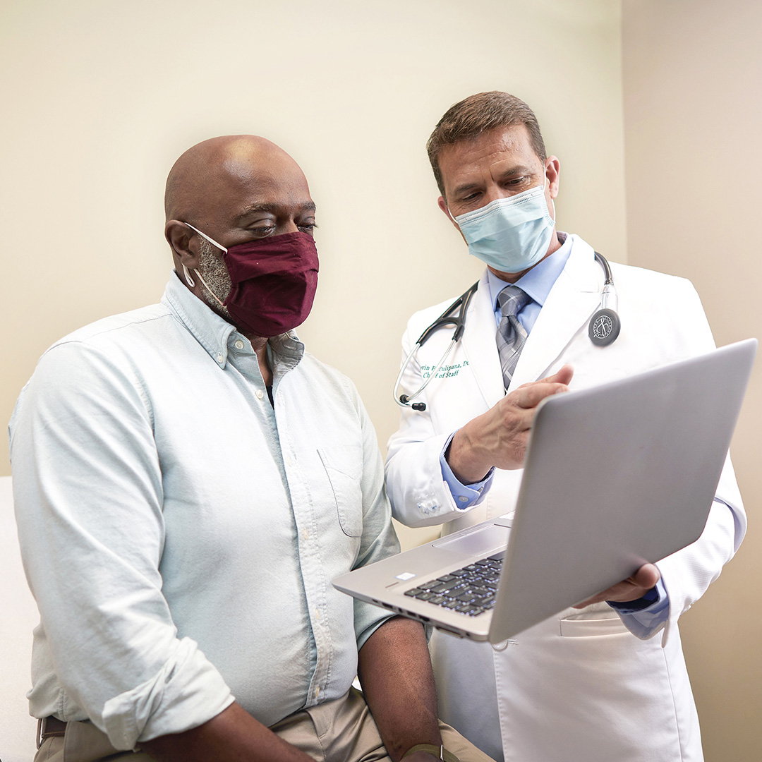 A male cancer patient reviews results with an oncologist.